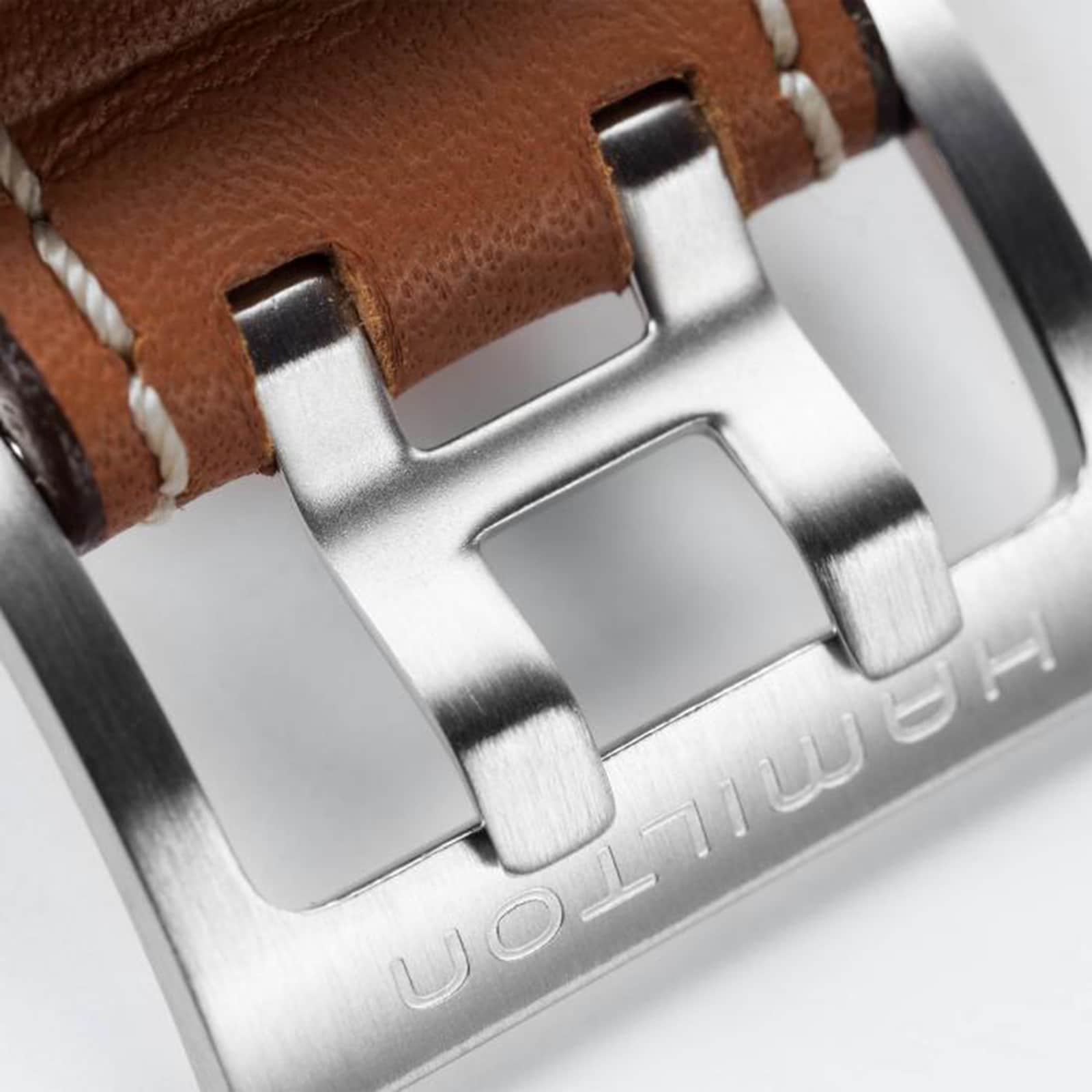 Close-up of the Hamilton Khaki Aviation X-Wind Auto Chrono’s brushed metal buckle, paired with a brown leather strap and white stitching—highlighting the precision craftsmanship of this automatic chronograph.