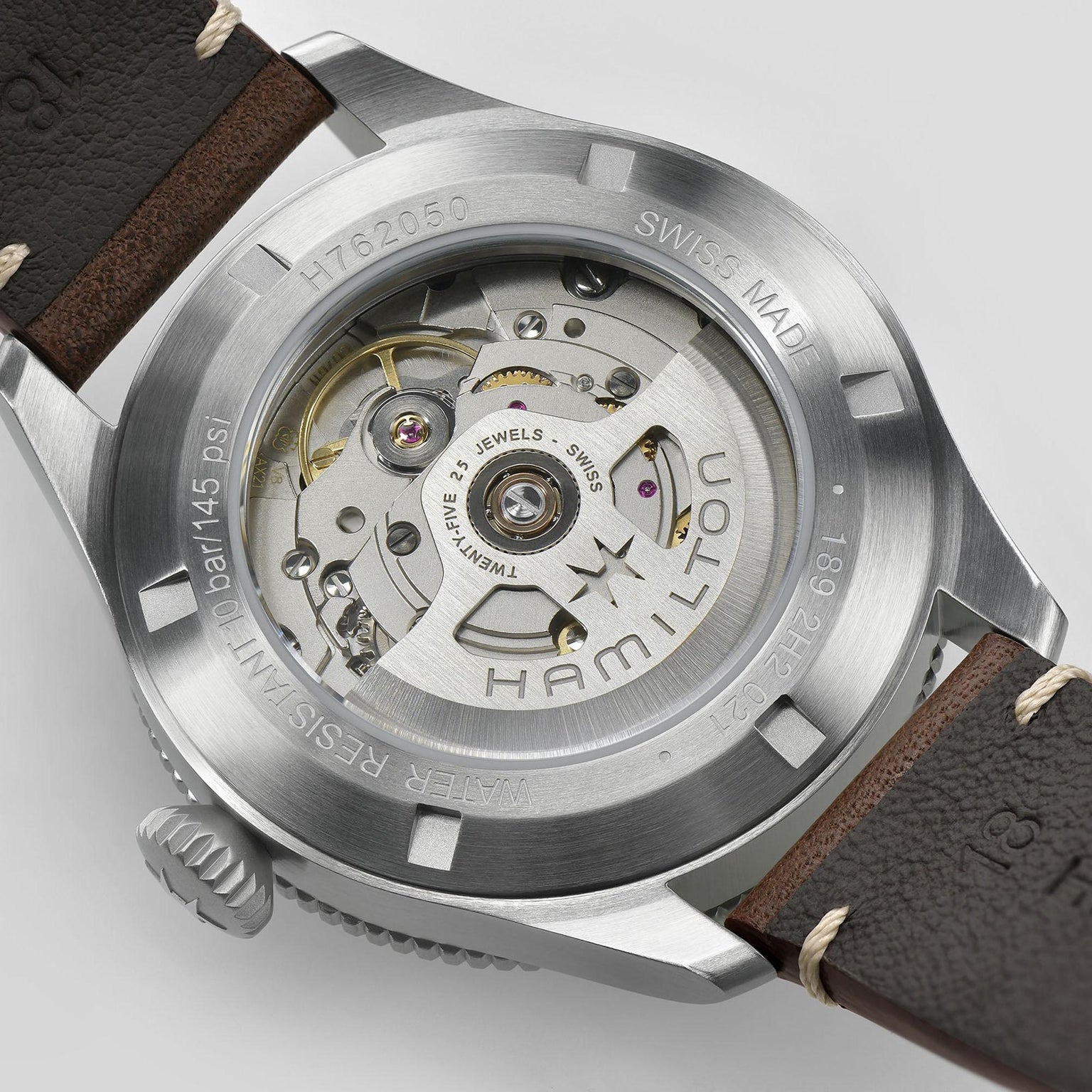 Close-up of the Hamilton Khaki Aviation Pilot Pioneer watch’s back, highlighting its automatic movement, metal case, visible gears, and engravings about water resistance and Swiss made—capturing its aviation-inspired design.