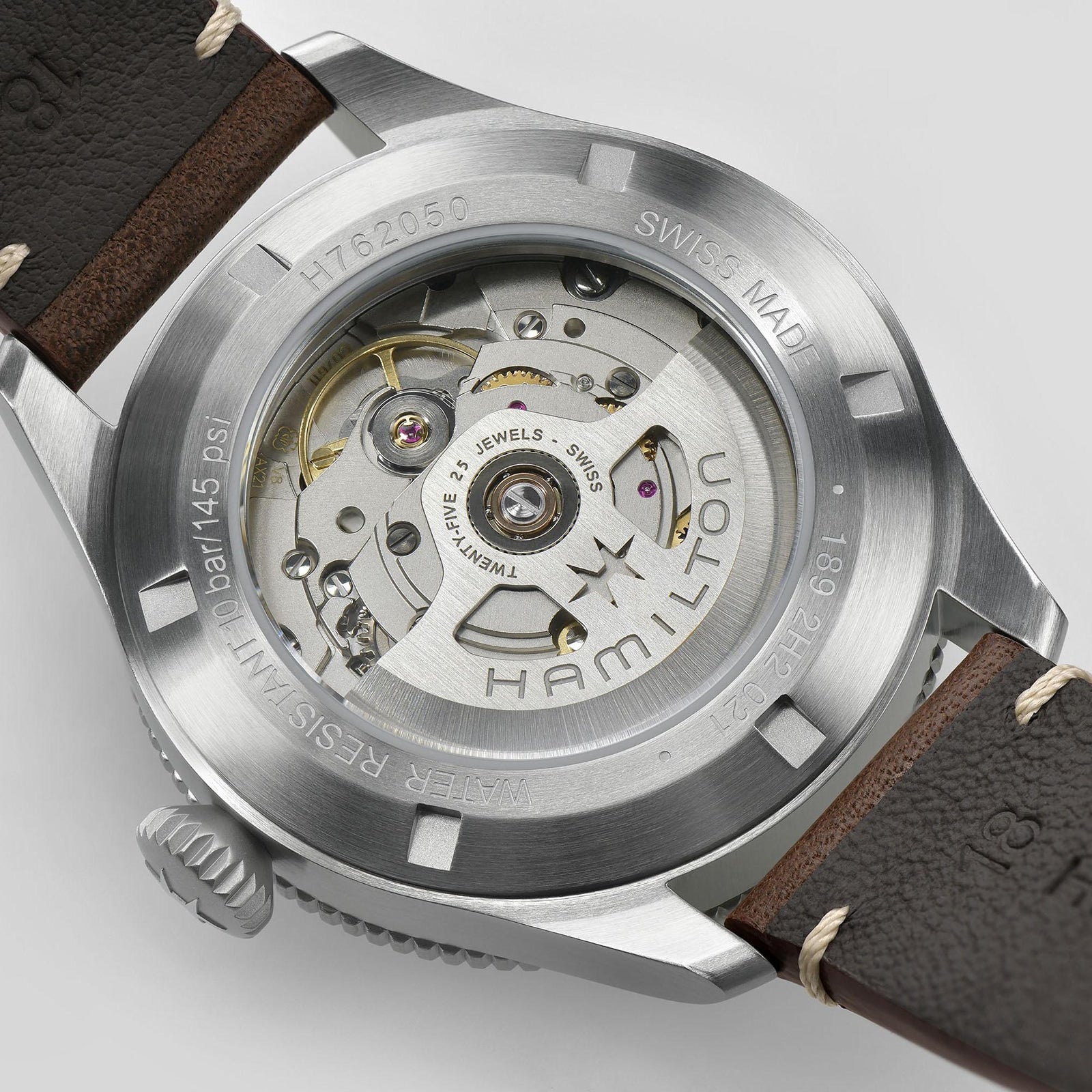 Close-up of the Hamilton Khaki Aviation Pilot Pioneer watch’s back, highlighting its automatic movement, metal case, visible gears, and engravings about water resistance and Swiss made—capturing its aviation-inspired design.