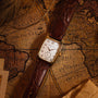A Hamilton American Classic Boulton Quartz wristwatch with a brown leather strap lies on an old, sepia-toned world map depicting Africa and the Atlantic Ocean.
