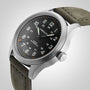 Close-up of a Hamilton Khaki Field Titanium Auto watch featuring a black dial, titanium case, olive green fabric strap, and white hour numerals.