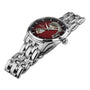 The Hamilton Jazzmaster Open Heart Auto, featuring a red gradient dial, visible mechanical movement, and stainless steel link bracelet, is displayed at an angle on a white background.