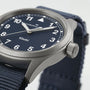 Close-up of the Hamilton Khaki Field Quartz 38mm, featuring a blue dial with white numerals and a robust blue NATO strap—showcasing its military-inspired design. The time on the watch is about 10:09:35.