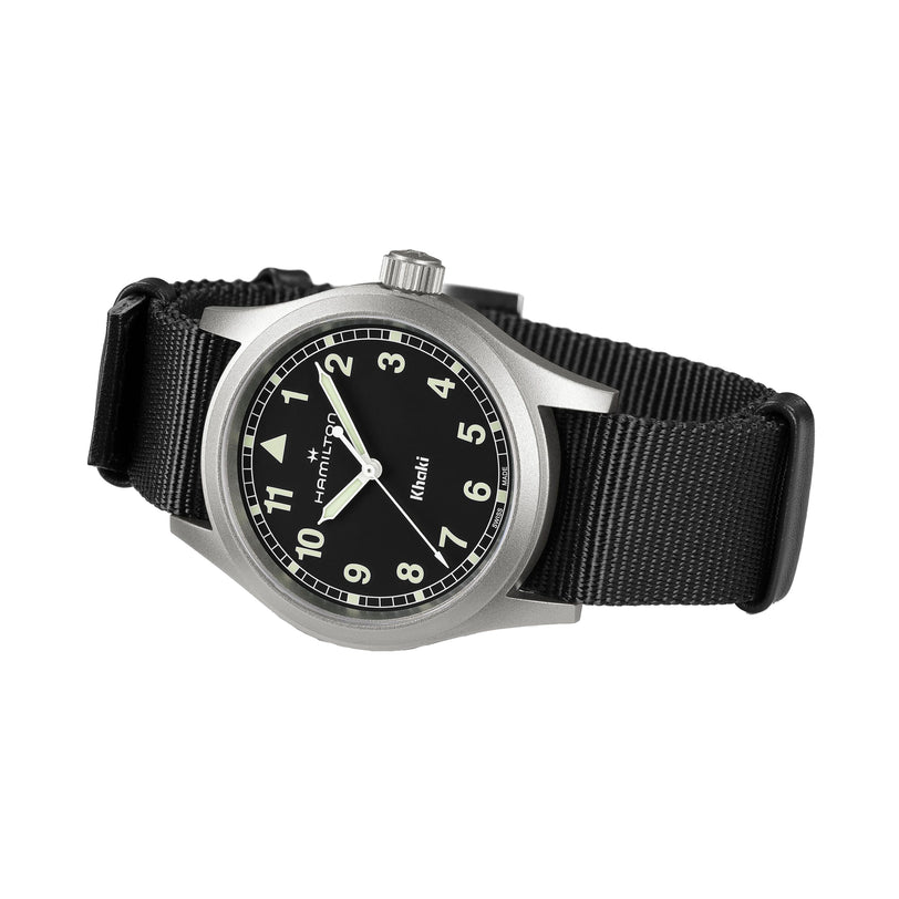 The Hamilton Khaki Field Quartz watch features a black dial with white numerals and a black nylon strap, displayed at an angle.