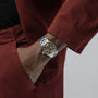 A person in a red outfit has their left hand, wearing a Hamilton Khaki Field Auto 38mm watch, in their pocket.