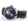 The Hamilton Jazzmaster Open Heart Auto 42mm is a silver wristwatch with a blue leather strap and speckled dial, featuring exposed gears through cut-out sections and powered by automatic movement—blending elegance and innovation.