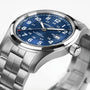 The Hamilton Khaki Field Auto 42mm, featuring a stainless steel case, blue dial with white numerals, H-10 automatic movement, date display, and a metal link bracelet, is angled to highlight its military-inspired design.