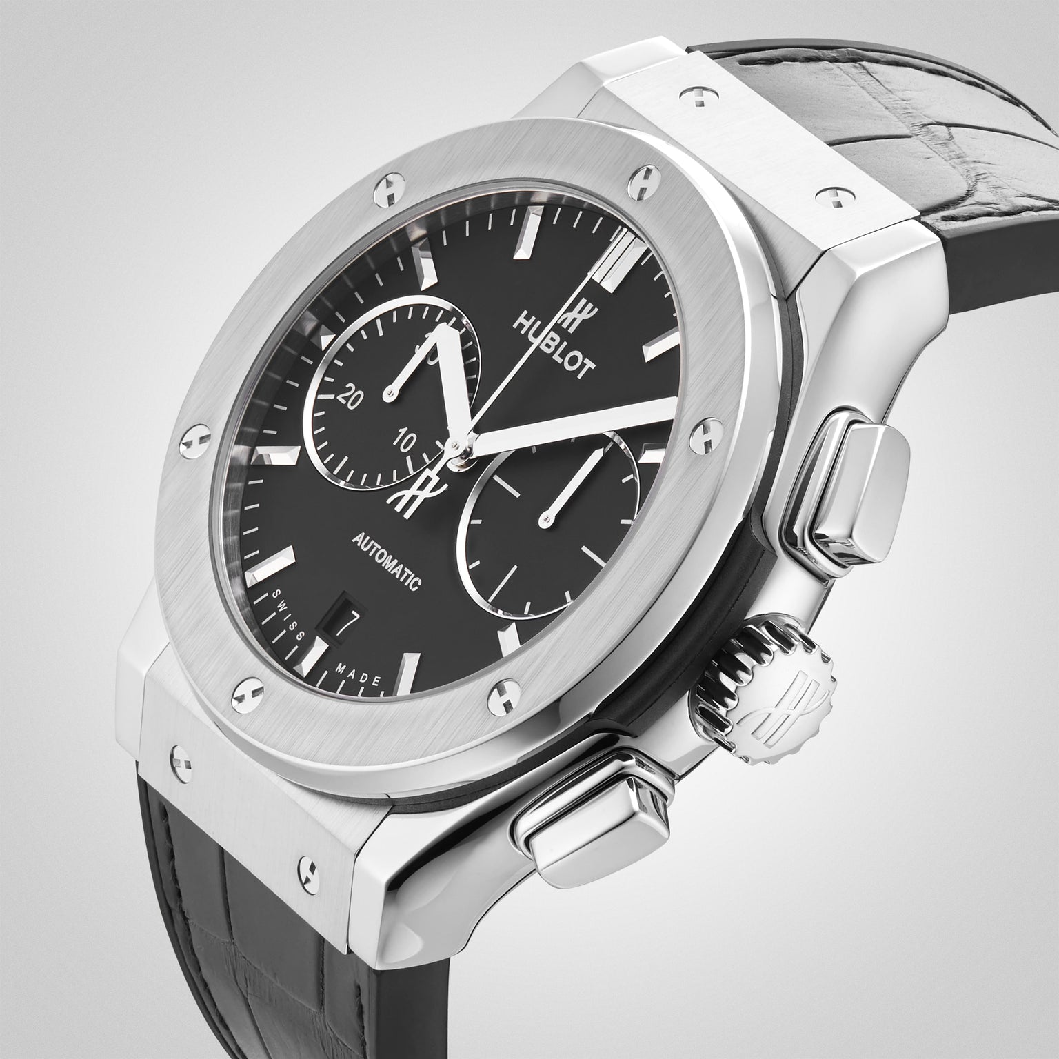 A Hublot Classic Fusion Chronograph Titanium wristwatch featuring a black dial, silver titanium case, and black leather strap displayed on a light background.