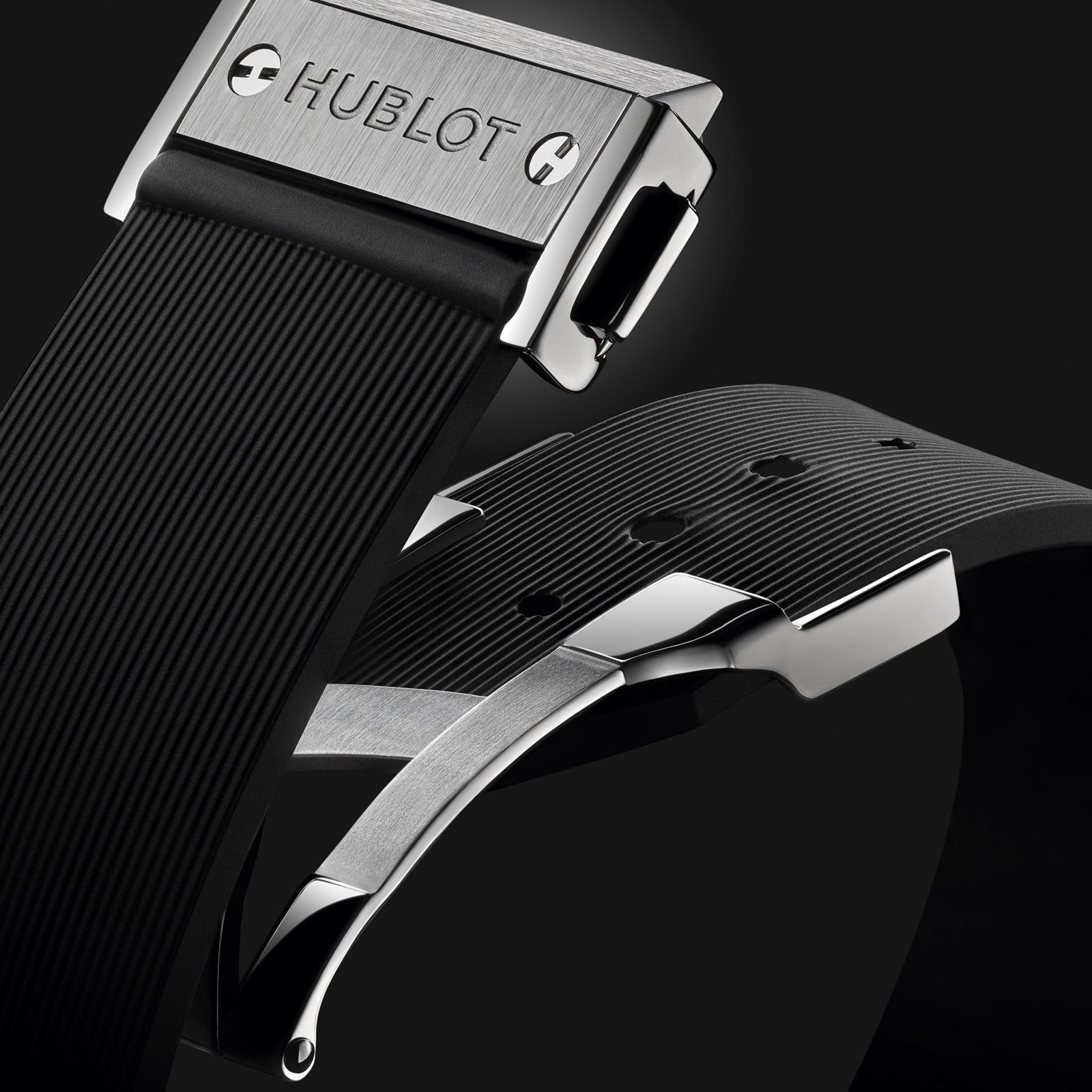Close-up of a Hublot Classic Fusion Titanium watch clasp and black rubber strap, showcasing the brand logo and metallic clasp details against a dark background.