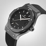 A close-up of the Hublot Classic Fusion Black Magic wristwatch showcases its black ceramic round face, silver markers, and black rubber strap against a light gray background.