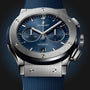 A close-up view of the Hublot Classic Fusion Chronograph Titanium Blue, featuring a blue sunray dial, titanium case, silver bezel, chronograph subdials, date window, and a textured blue strap.