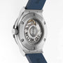 Back view of the Hublot Classic Fusion Titanium Blue, showing its self-winding movement through a transparent case back with visible engravings and a blue rubber strap. The titanium case brings modern elegance to this iconic watch.