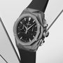 The Hublot Classic Fusion Chronograph Orlinski Titanium features a faceted gray case, black dial with two subdials, and a black rubber strap, all set against a minimalist light background.
