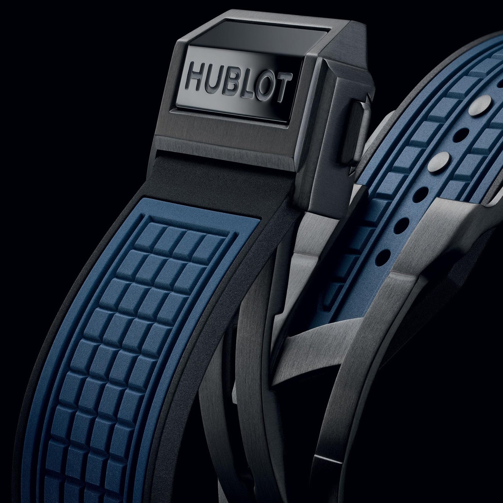 Close-up of a Hublot Square Bang Unico Blue Ceramic watch strap featuring a black and blue textured rubber design and a metallic clasp engraved with the Hublot logo.