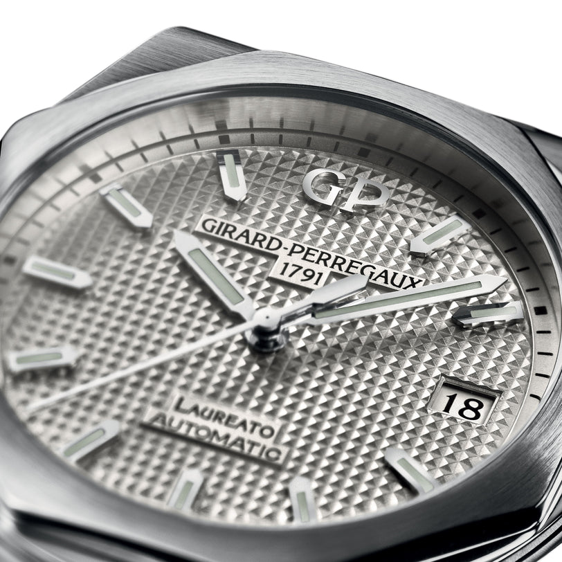 Close-up of the Girard-Perregaux Laureato 42 watch face, showcasing a silver textured dial, luminous hands and markers, date window at 3 o’clock, signature octagonal bezel, and refined branding in a stainless steel case.