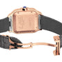 Close-up of a Santos de Cartier wristwatch by Cartier, showing its leather strap, 18K rose gold deployment clasp, engraved caseback details with calibre 1847 MC markings, and a blue gemstone set in the crown.