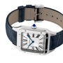 The Cartier Santos-Dumont features a silver square face, Roman numerals, blue hands, and a blue leather strap with mechanical movement, shown at an angle.
