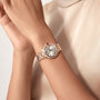 Close-up of a person wearing the Cartier Ballon Bleu de Cartier wristwatch in rose gold with automatic movement and Roman numerals, paired with a beige satin top.