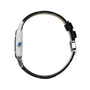 Side view of a minimalist Pasha de Cartier wristwatch by Cartier, featuring a black leather strap and blue gem on the crown, with clean geometric shapes against a white background.