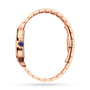 Side view of the Cartier Santos de Cartier Skeleton watch in rose gold, featuring a blue gemstone crown and a metal link band with SmartLink adjustment, displayed on a white background.
