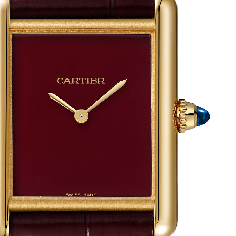 Close-up of the Cartier Tank Louis Cartier wristwatch, featuring an 18K yellow gold rectangular case, burgundy dial, gold hands, blue cabochon crown, and visible CARTIER and SWISS MADE markings.