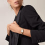 A woman poses with one hand on her blazer lapel, showcasing the La Panthère de Cartier gold watch by Cartier.