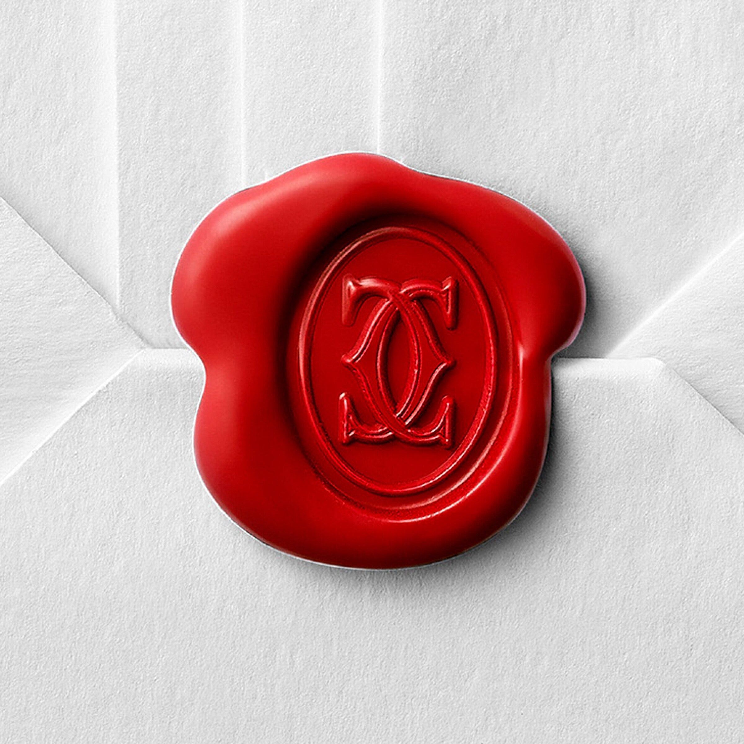 A red wax seal featuring Cartier’s interlocking double C monogram adorns a white envelope, inspired by the Tank Américaine.