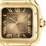 Close-up of the Santos de Cartier watch by Cartier in 18K yellow gold, featuring Roman numerals, a date display at 6 o’clock, and “Automatic” on the dial.