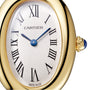 Close-up of the Cartier Baignoire watch, featuring an 18K yellow gold oval case, blue hands, Roman numeral hour markers, and a crown adorned with a blue cabochon gemstone.