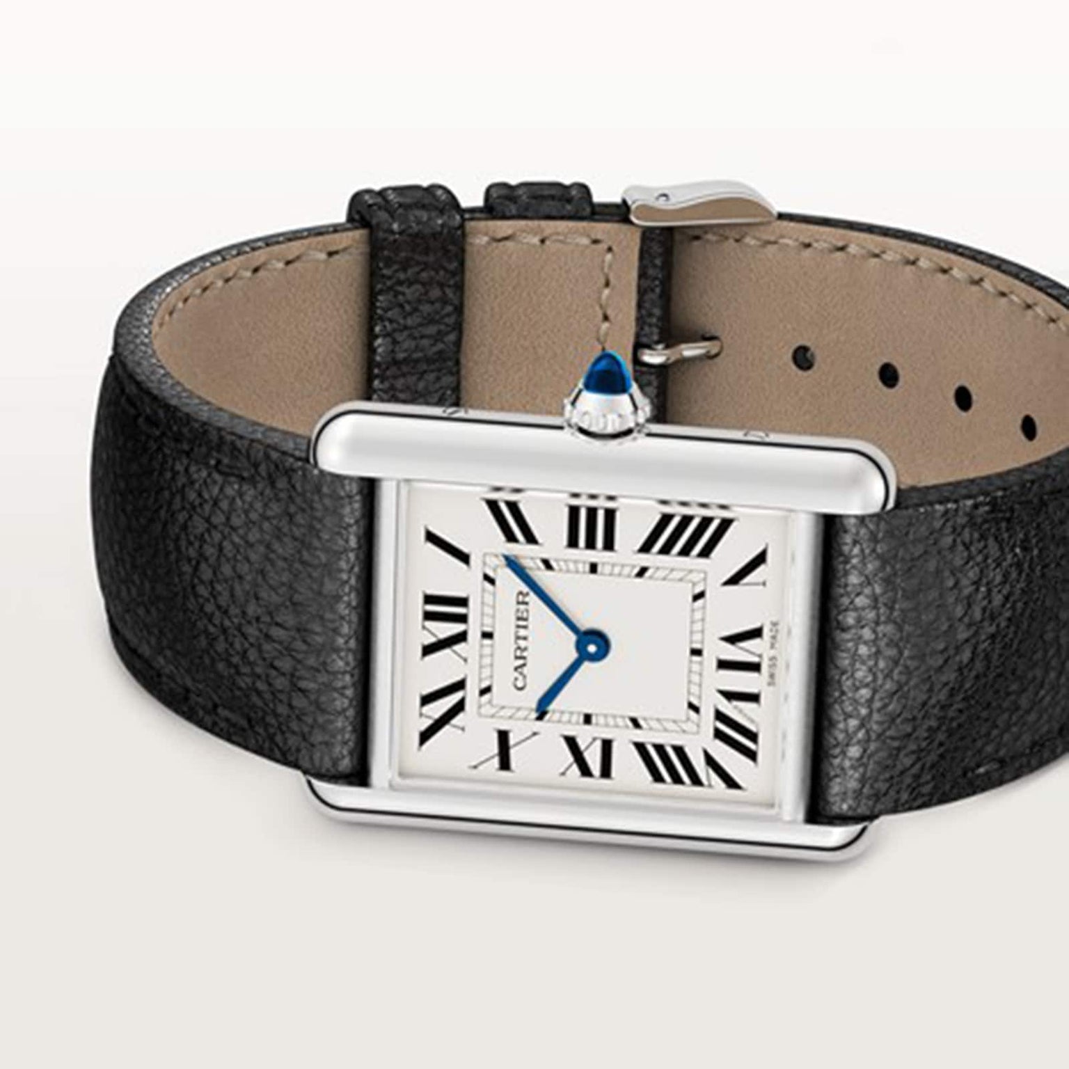 A Cartier Tank Must de Cartier watch with a square face, Roman numerals, blue sword-shaped hands, quartz movement, and a black leather strap is displayed on a light background.