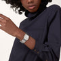 A person in a dark long-sleeve shirt is shown from the shoulders down, wearing the Cartier Tank Française watch against a plain background.