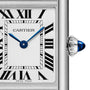 Close-up of a Cartier Tank Must Solarbeat™ watch face featuring Roman numerals, blue sword-shaped hands, a steel case, and a crown adorned with a blue cabochon.