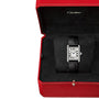 The Cartier Tank Must de Cartier wristwatch features a rectangular steel case and black band, presented in an open red Cartier box with a velvet interior.