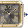 Close-up of the Cartier Santos-Dumont watch face, featuring gold Roman numerals, gold hands, an 18K yellow gold bezel, and a blue gemstone crown on the right—a hallmark of Cartier craftsmanship.