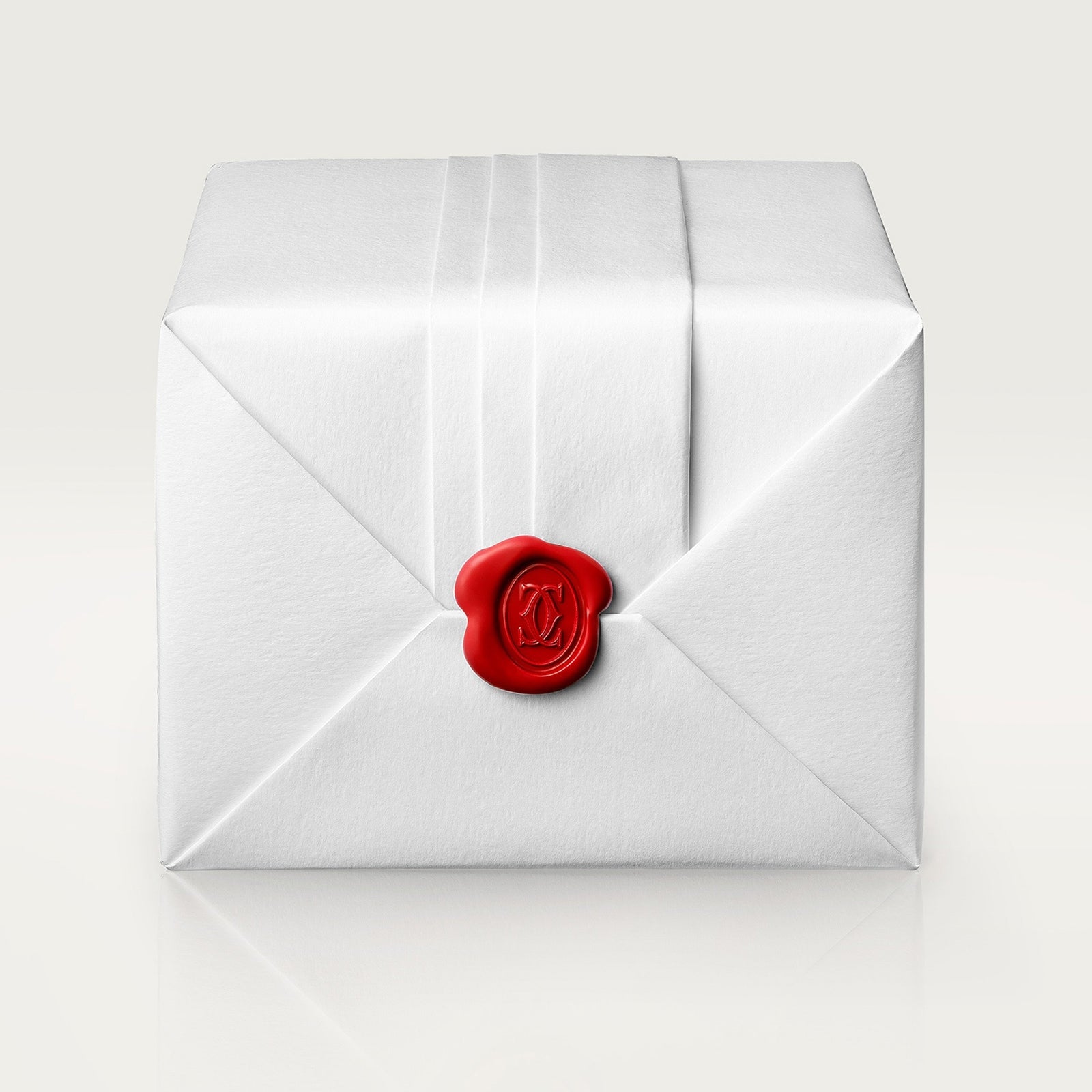 A white rectangular package tied with string and sealed with a red wax seal evokes the refined elegance of Cartier’s Santos-Dumont watch.