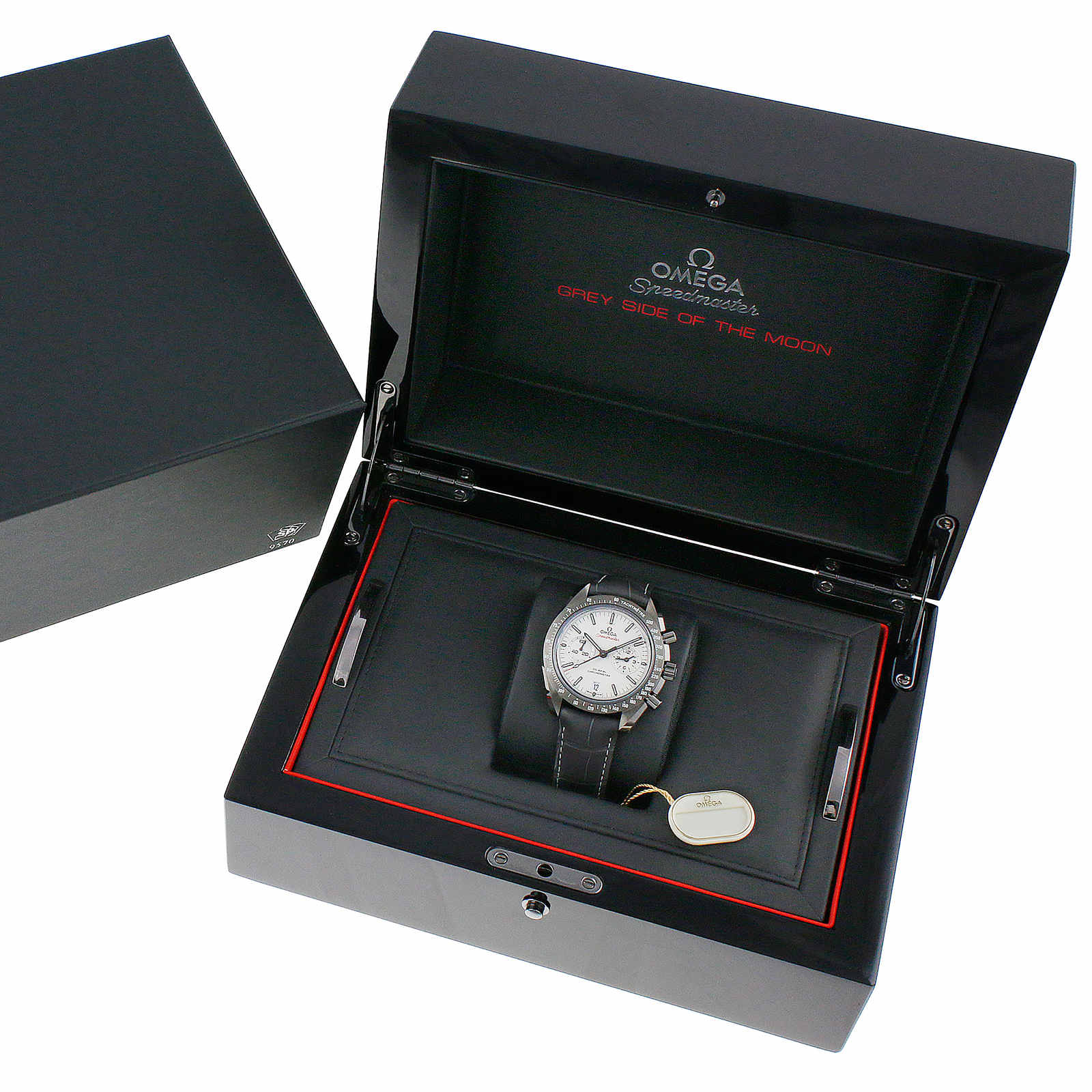 The OMEGA Speedmaster Dark Side of the Moon Grey Side Edition is shown in an open black presentation box with red accents, accompanied by a tag and documents, and features the advanced Co-Axial calibre 9300 movement.