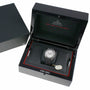 The OMEGA Speedmaster Dark Side of the Moon Grey Side Edition is shown in an open black presentation box with red accents, accompanied by a tag and documents, and features the advanced Co-Axial calibre 9300 movement.