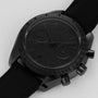 An OMEGA Speedmaster Dark Side of the Moon Black Black wristwatch, featuring a black dial, strap, and bezel, is photographed on a light background.