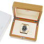 An OMEGA Seamaster Planet Ocean 600M stainless steel dive watch is shown in an open wooden presentation box with a cream interior, next to a white branded box.