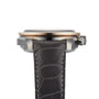 Side view of the OMEGA Speedmaster Dark Side of the Moon Meteorite with a round ceramic case, right-side crown, and black leather strap featuring white stitching.