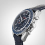 A close-up of the OMEGA Speedmaster Moonphase wristwatch with a blue leather strap, blue dial, tachymeter bezel, and chronograph subdials, featuring Master Chronometer certification against a plain gradient background.