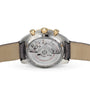 Back view of an OMEGA Speedmaster Moonphase wristwatch, displaying the exposed mechanical movement with a leather strap and 18K yellow gold crown.