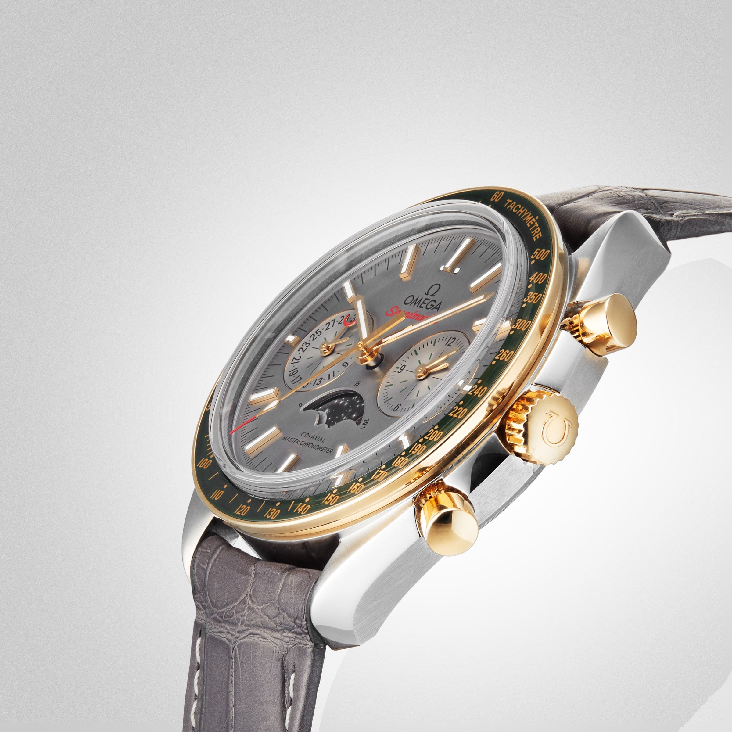 The OMEGA Speedmaster Moonphase is a luxury wristwatch with a grey leather strap, silver dial featuring multiple subdials and a Moonphase display, and distinguished by its 18K yellow gold bezel and pushers.