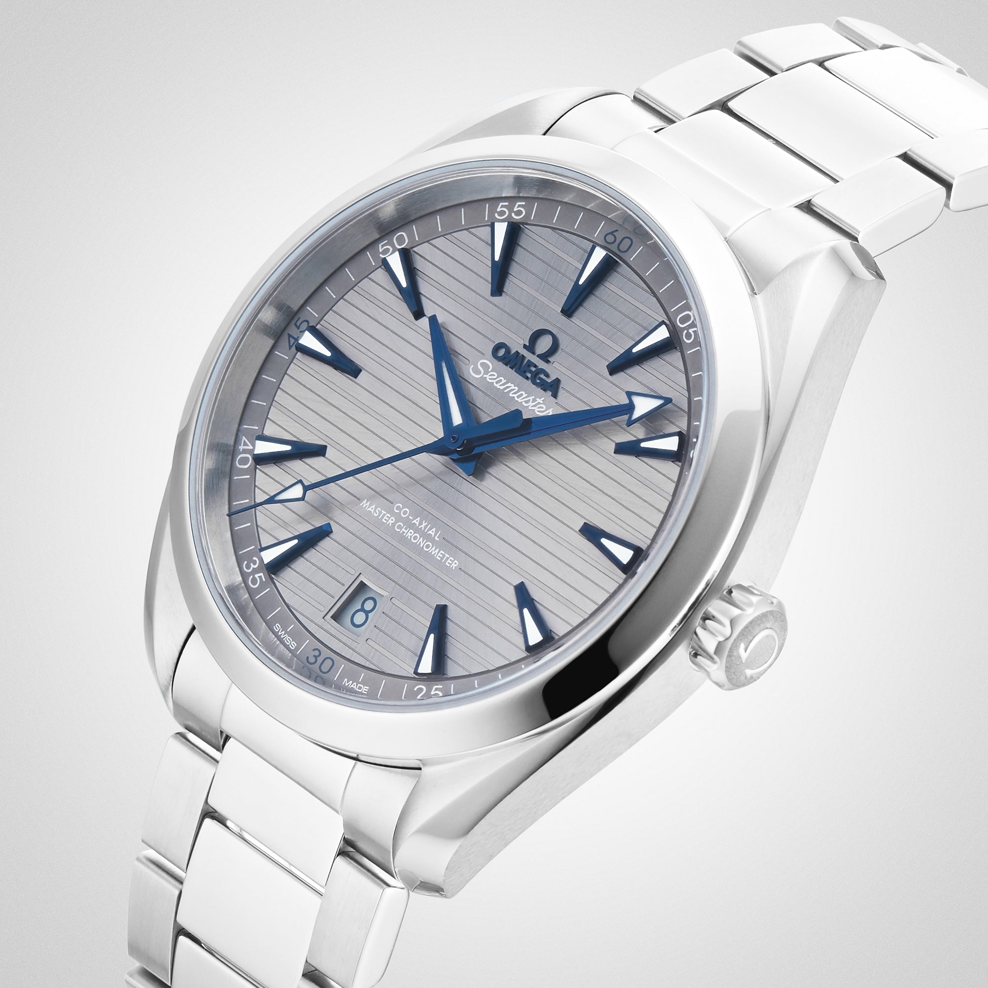 The OMEGA Seamaster Aqua Terra 150M features a striped light gray dial, blue hands and markers, date window at 6 o’clock, stainless steel bracelet, and master chronometer certification inspired by maritime heritage.
