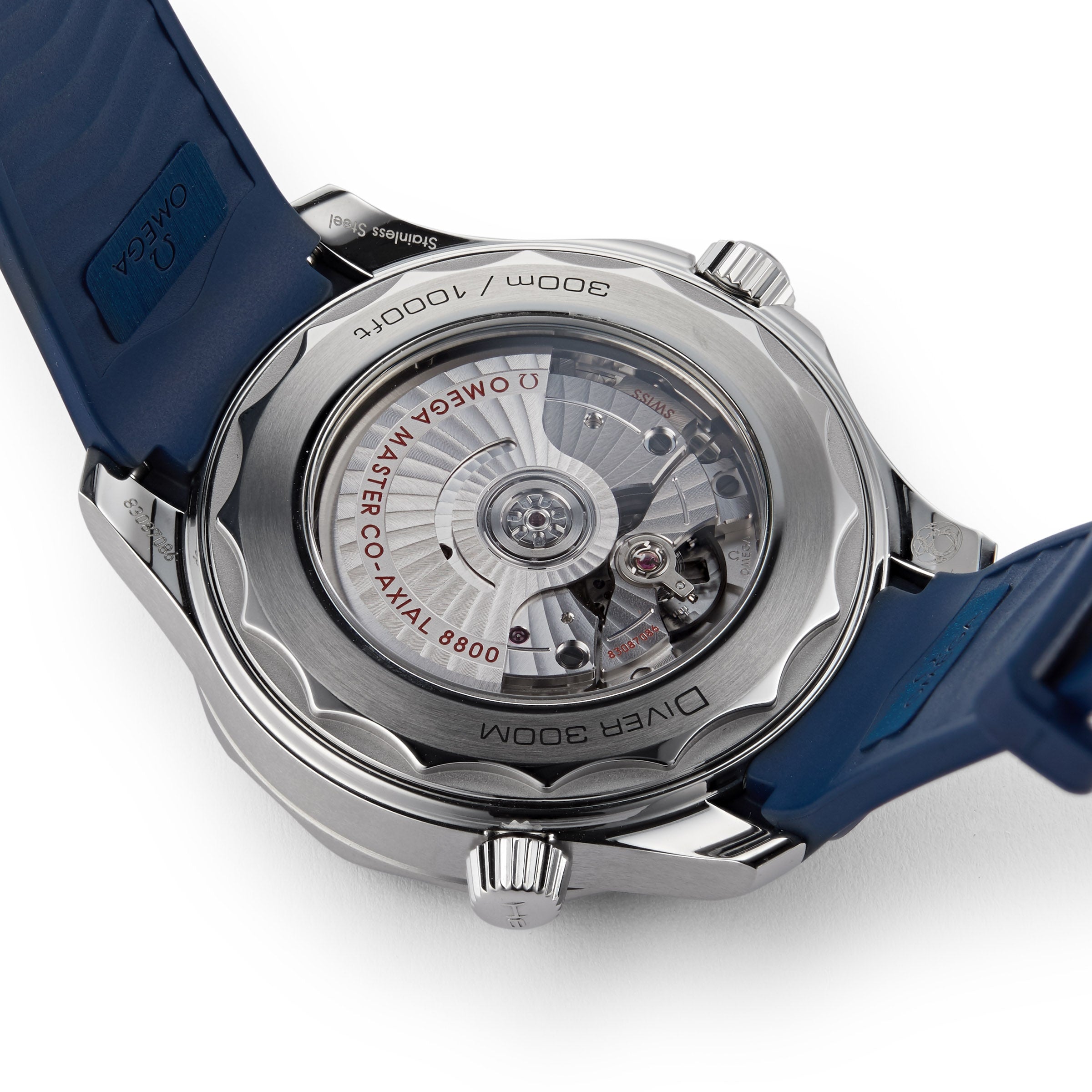 Close-up of the back of an OMEGA Seamaster Diver 300M wristwatch with a transparent case revealing its movement and engraved text, attached to a blue strap.