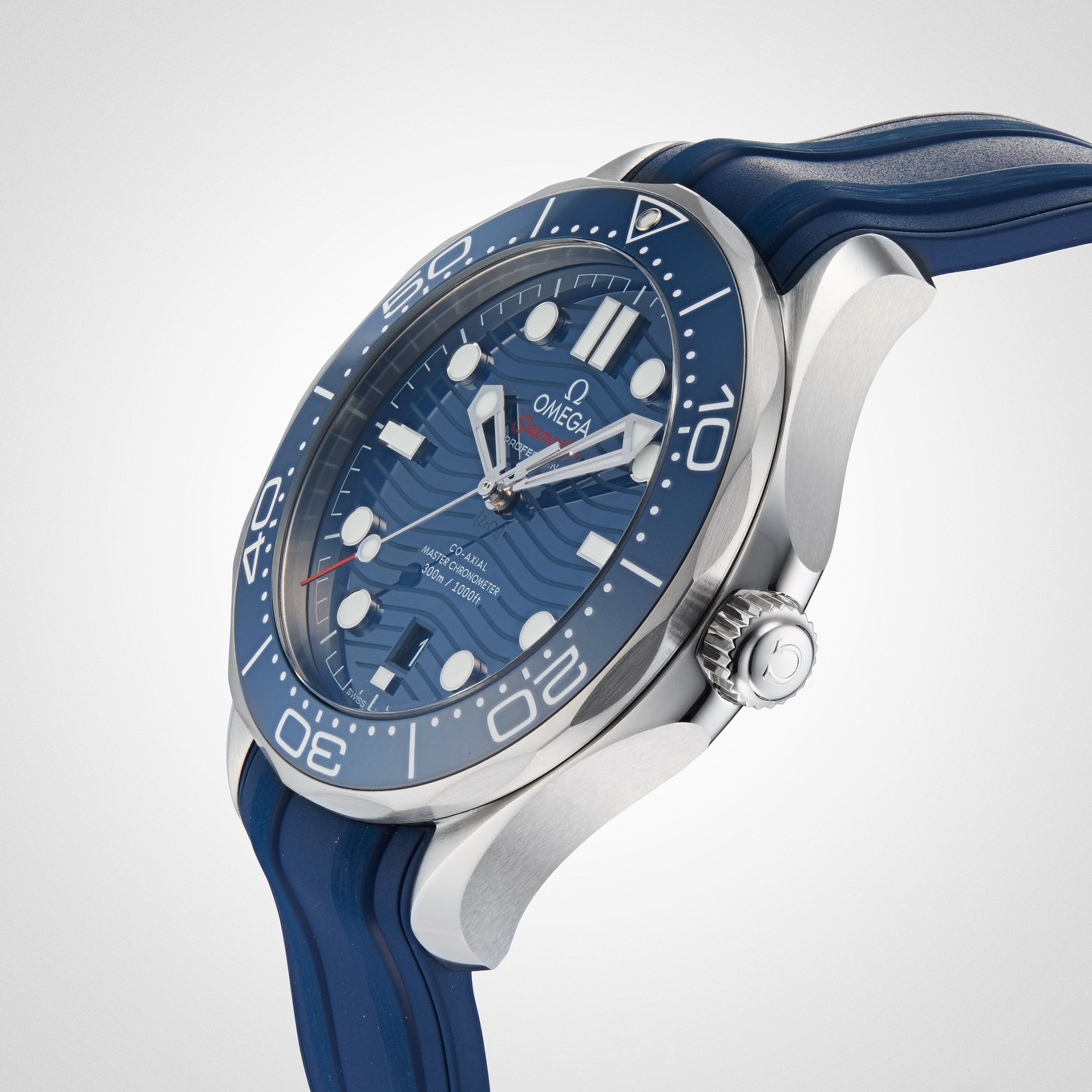 A close-up of the OMEGA Seamaster Diver 300M, featuring a blue face, blue bezel, and blue rubber strap with the precise Calibre 8800 movement, angled on a plain light background.