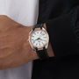 A person wearing an OMEGA Seamaster Aqua Terra 150M with a silver case, white dial, black Roman numerals, black strap, and a black jacket.