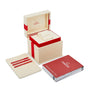 An open OMEGA watch box with a cream and red interior is displayed next to a cream cardholder and red-silver booklet—ideal for storing your Constellation timepieces.