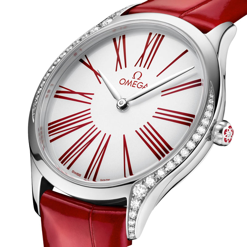 Close-up of the OMEGA De Ville Tresor 36 watch featuring a white dial, red Roman numerals, red leather strap, and a diamond-set bezel.