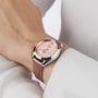 Someone wearing a long-sleeved white shirt and a pink leather OMEGA Seamaster Aqua Terra 150M featuring a rose gold face with a silver case.